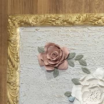 A rose in the corner beside the carved gold frame