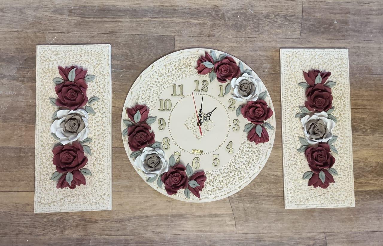 A round clock flanked by two tall panels decorated with burgundy and ivory roses