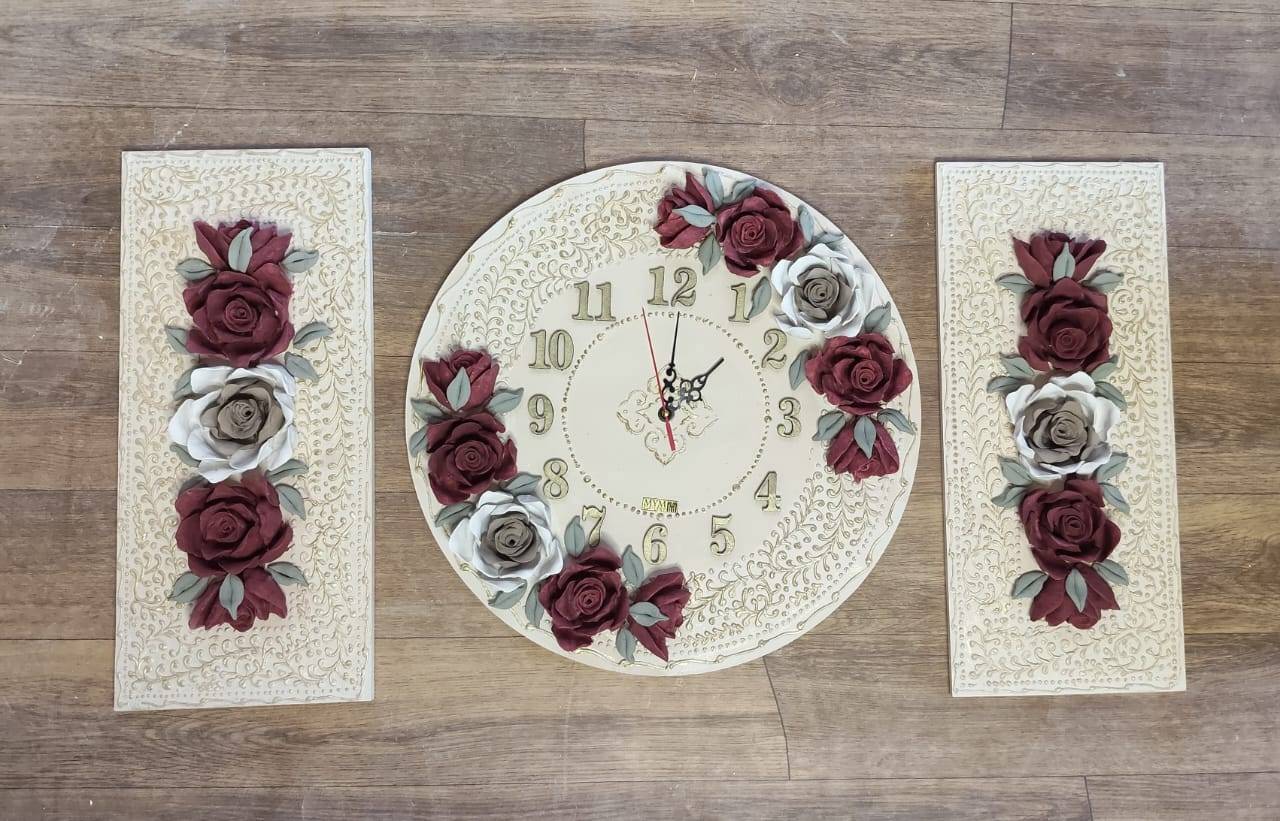 A round clock flanked by two tall panels decorated with burgundy and ivory roses